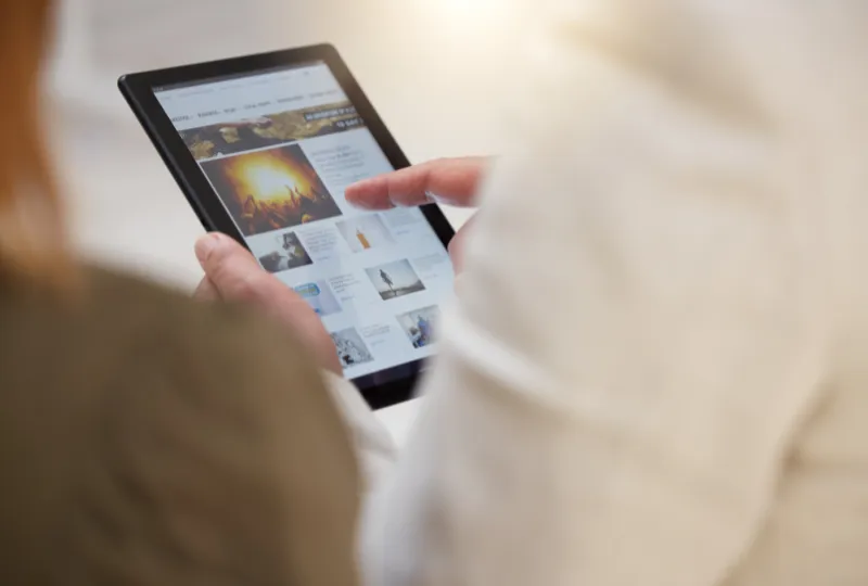 Person holding a tablet which has an article on it.
